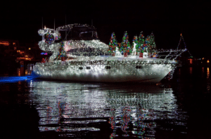 White boat decorated in christmas lights with christmas trips on the deck of the boat.