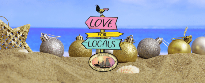 Christmas ornaments sitting on a beach with a Historic Seaport love for locals logo in the front of the picture.
