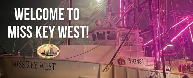 miss key west shrimp boat lit up in purple at night.