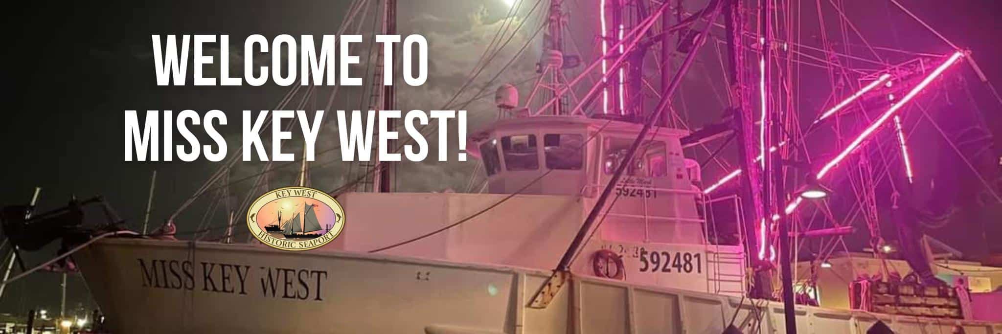 miss key west shrimp boat lit up in purple at night.
